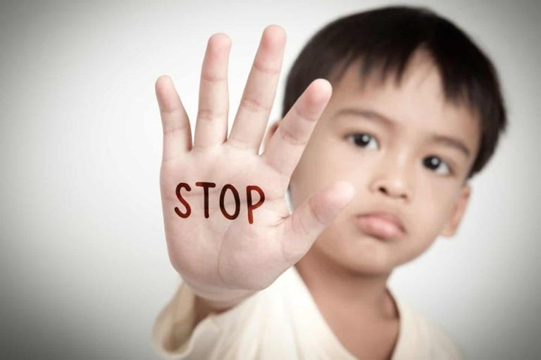 young boy holding hand up with stop wording written on