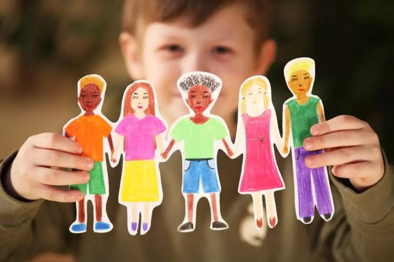 young boy holding paper cutout of family figures