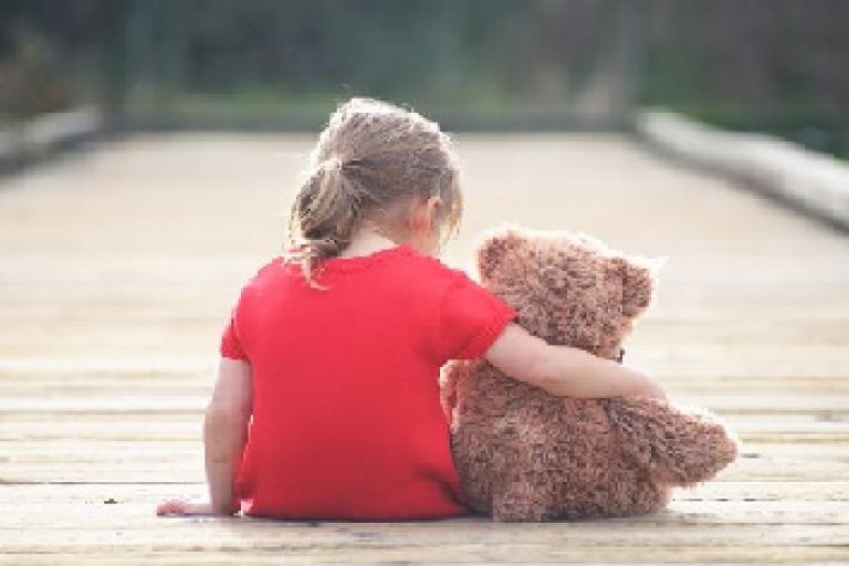 little girl arm around teddy bear