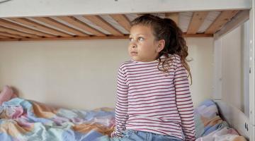 little girl sitting on bed home along.jpg